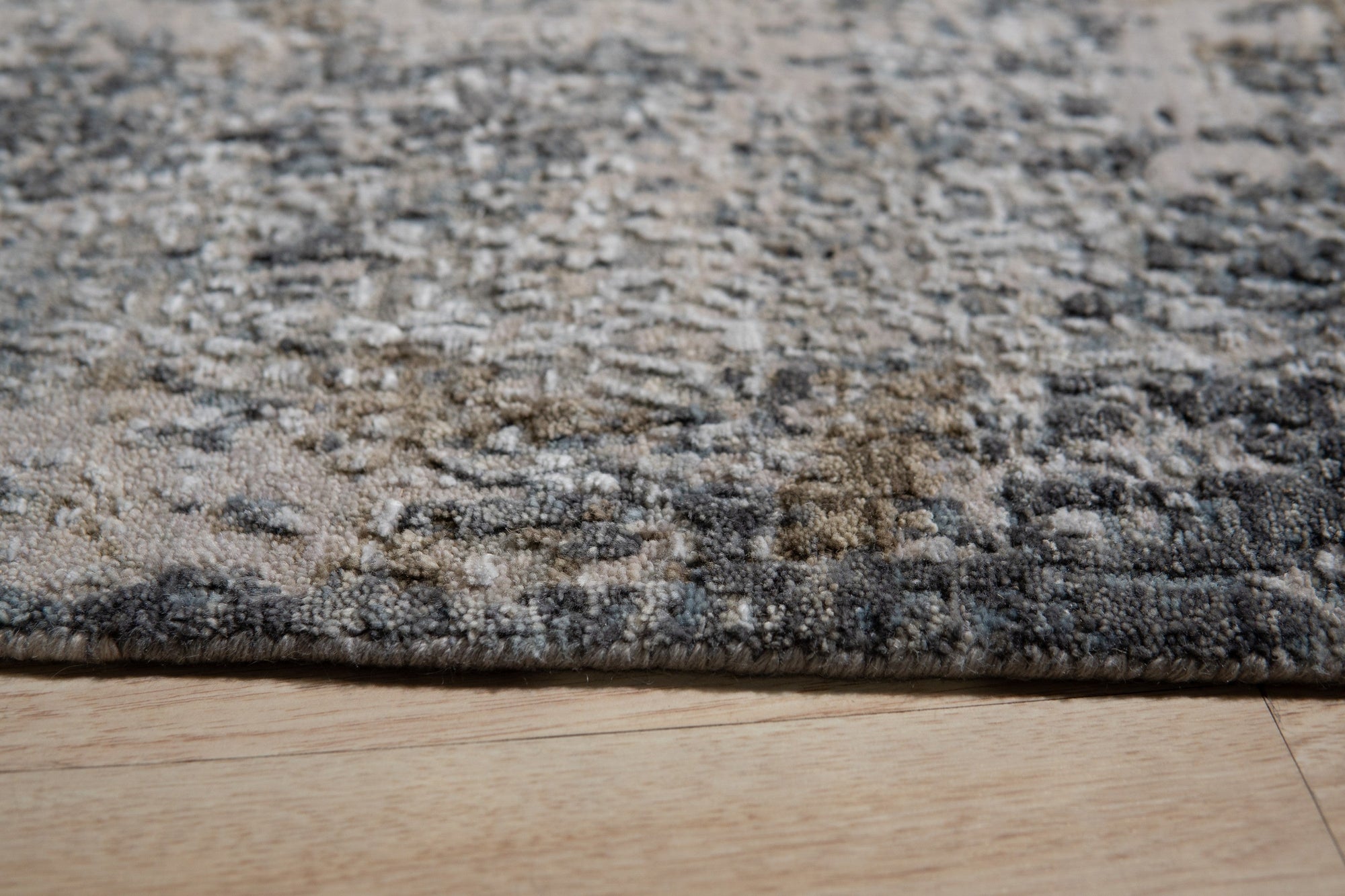 Xena Chloe Gray Hand Knotted Wool Rug displayed in a bright, modern living space. Soft gray hues mingle in the hand-knotted wool, creating a subtly textured floor covering that complements the light-filled room.