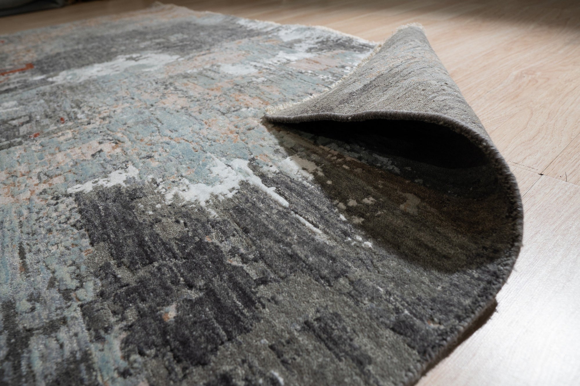Xena Chloe Gray Hand Knotted Wool Rug anchors a bright living space; warm natural light illuminates the gray and ivory tones of the hand-knotted wool, complementing the minimalist decor.