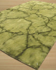 Sleek Cozy Green Hand Knotted Wool Rug, displaying a subtly textured green surface woven from soft wool, resting on a light wooden floor with a hint of natural light illuminating its cozy fibers.