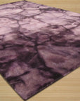 Opulent Rhea Purple Hand Knotted Wool Rug, saturated purple wool displaying intricate hand-knotted details, bathed in soft light, showcasing its luxurious texture and rich color depth.