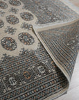 Rustic Nina Beige Nan Rug lays in a softly lit room, its subtle beige tones and textured weave lending a warm, inviting feel to the space. The neutral palette and understated design complement the surrounding minimalist decor.