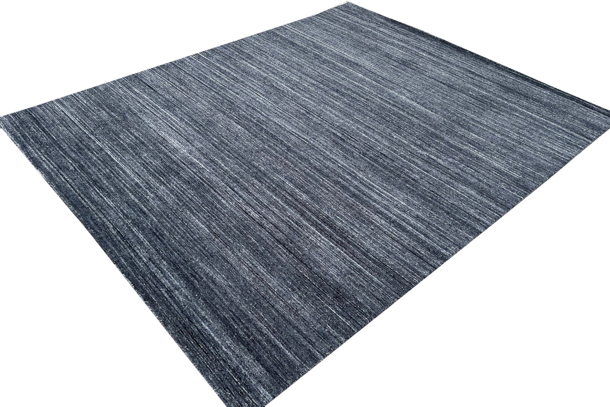 Delicate Striped Charcoal Handmade Wool Rug, its deep charcoal stripes creating a subtle, textural contrast across the hand-woven wool surface, lending sophisticated warmth to a light-filled space.
