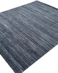 Delicate Striped Charcoal Handmade Wool Rug, its deep charcoal stripes creating a subtle, textural contrast across the hand-woven wool surface, lending sophisticated warmth to a light-filled space.