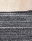 Delicate Striped Charcoal Handmade Wool Rug, displays textured charcoal stripes across a soft wool surface, hand-knotted for durability and subtle sophistication.
