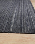 Delicate Striped Charcoal Handmade Wool Rug, presenting charcoal and ivory stripes in a handwoven wool construction, lies flat on a light surface, accentuating its subtle texture and refined color palette.