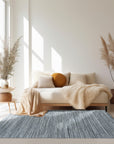 Delicate Striped Gray Handmade Wool Rug displayed on a light hardwood floor. Soft gray stripes run horizontally across the wool rug, creating a subtle, textured pattern.