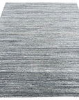 Delicate Striped Gray Handmade Wool Rug, a soft, textured wool rug with alternating shades of gray stripes, subtly hand-woven, lying flat on the floor.