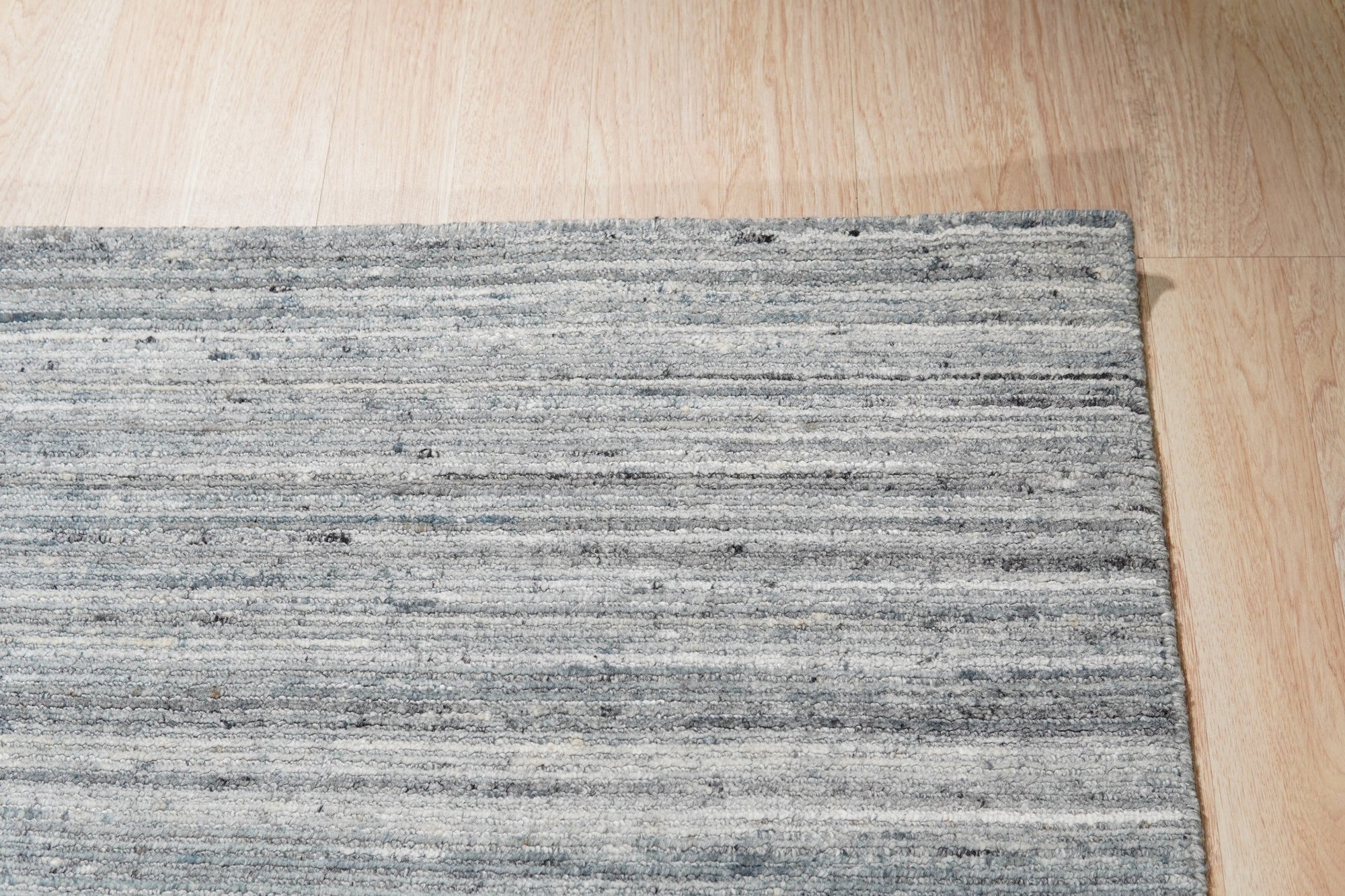 Delicate Striped Gray Handmade Wool Rug displayed in a bright, modern living room setting. Hand-knotted wool rug features subtle gray stripes against a lighter neutral background, adding texture and warmth to the space.