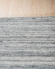 Delicate Striped Gray Handmade Wool Rug displayed in a bright, modern living room setting. Hand-knotted wool rug features subtle gray stripes against a lighter neutral background, adding texture and warmth to the space.