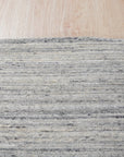 Delicate Striped Ivory Handmade Wool Rug, its soft ivory stripes creating a calming rhythm on the handwoven wool texture, showcased on hardwood flooring in a brightly lit space.