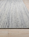 Delicate Striped Ivory Handmade Wool Rug, showcasing its subtly striped pattern and soft ivory hue, laid on a light wood floor with warm, inviting light emphasizing the wool's texture.