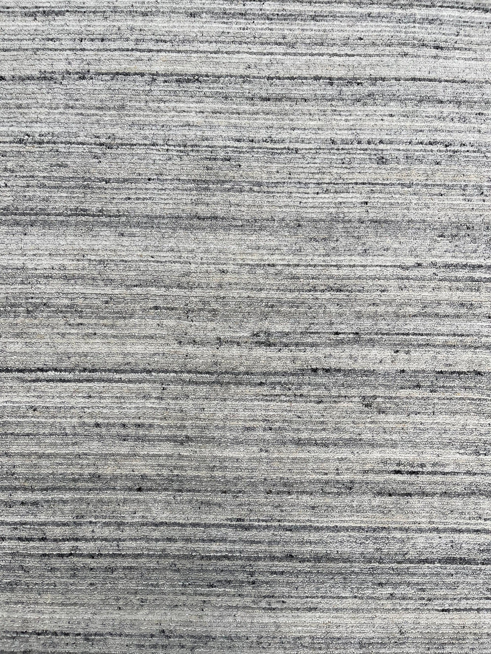 Delicate Striped Silver Handmade Wool Rug displayed in a bright room, its subtle silver stripes catching the light and showcasing the soft wool texture.