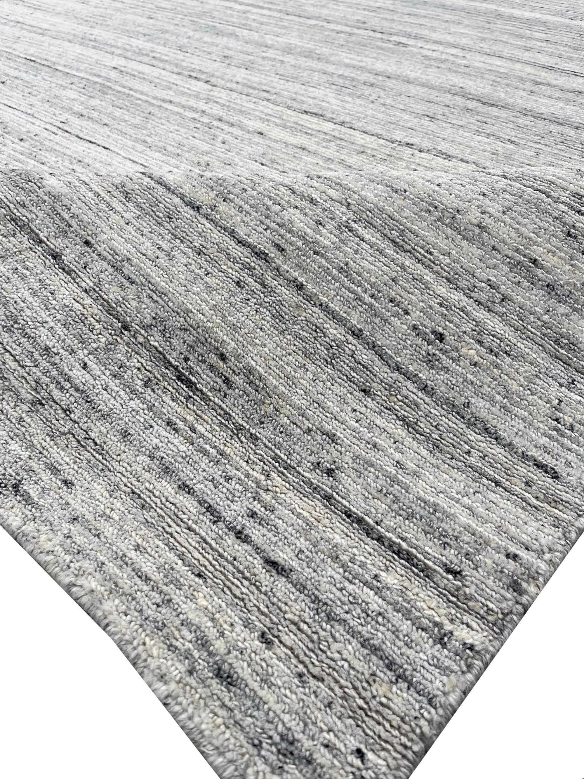 Delicate Striped Silver Handmade Wool Rug, its cool silver and ivory stripes lending subtle sophistication to a bright, neutral room setting.