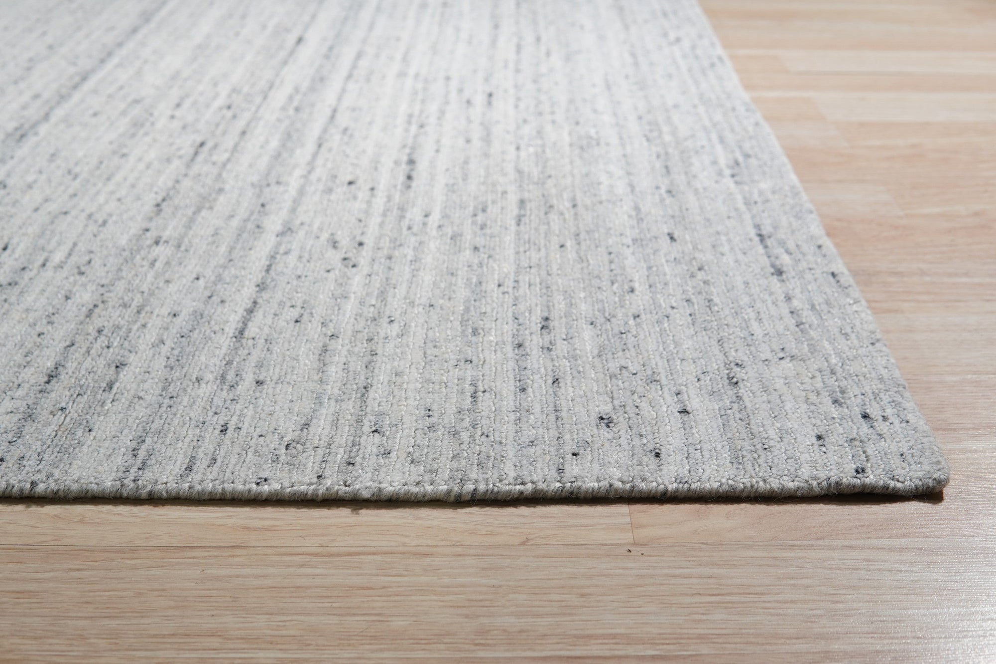 Delicate Striped Silver Handmade Wool Rug, its subtle silver stripes and plush wool texture bringing understated elegance to a bright, airy living room space.