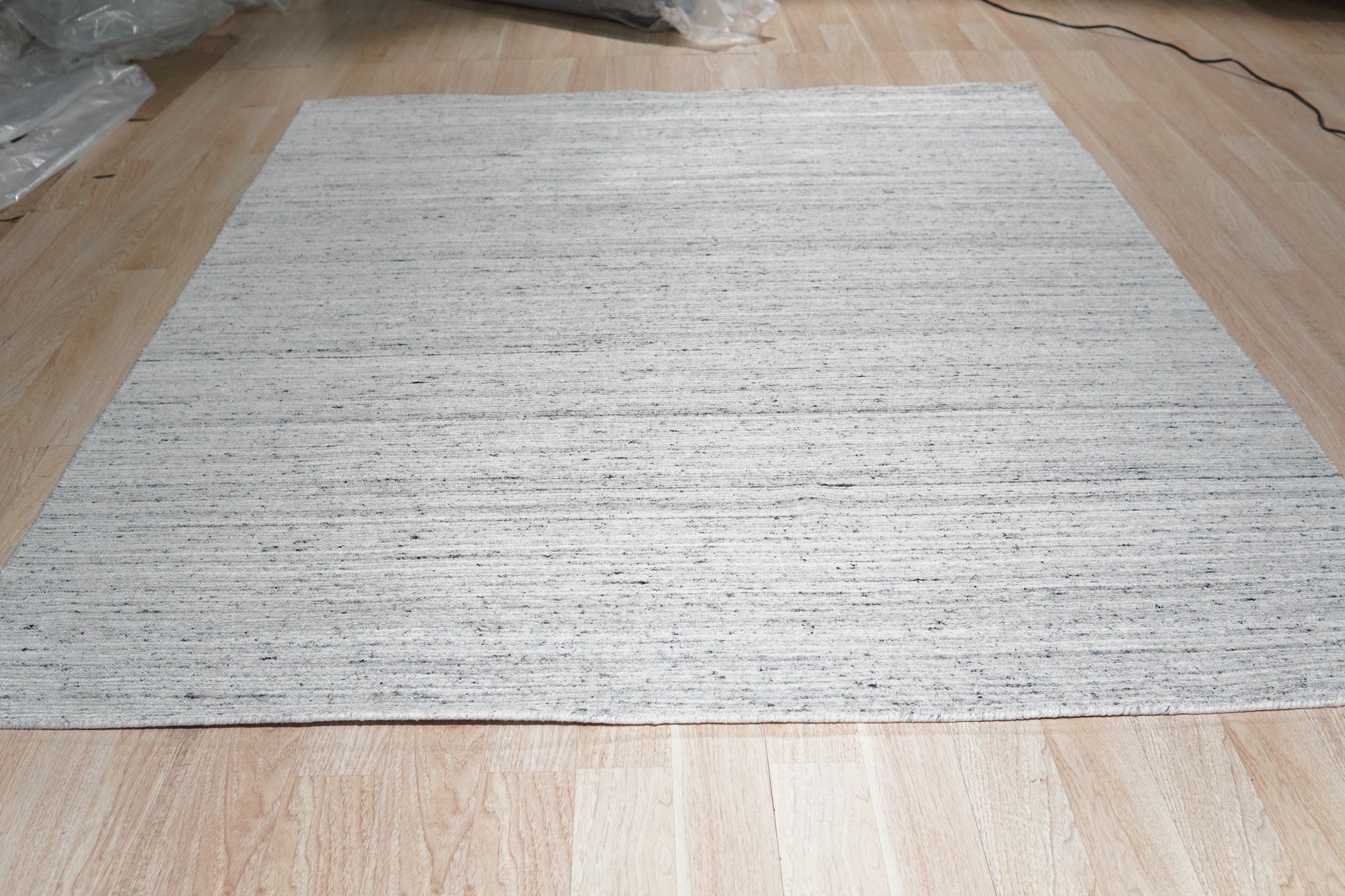 Delicate Striped Silver Handmade Wool Rug, its subtle silver stripes adding a touch of refined texture, captured within a bright, modern interior.