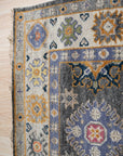 Lila Ruby Charcoal Hand Knotted Wool Rug, showing deep charcoal hues interwoven with subtle ruby accents. Hand-knotted construction creates a luxurious texture and intricate pattern across the wool pile.