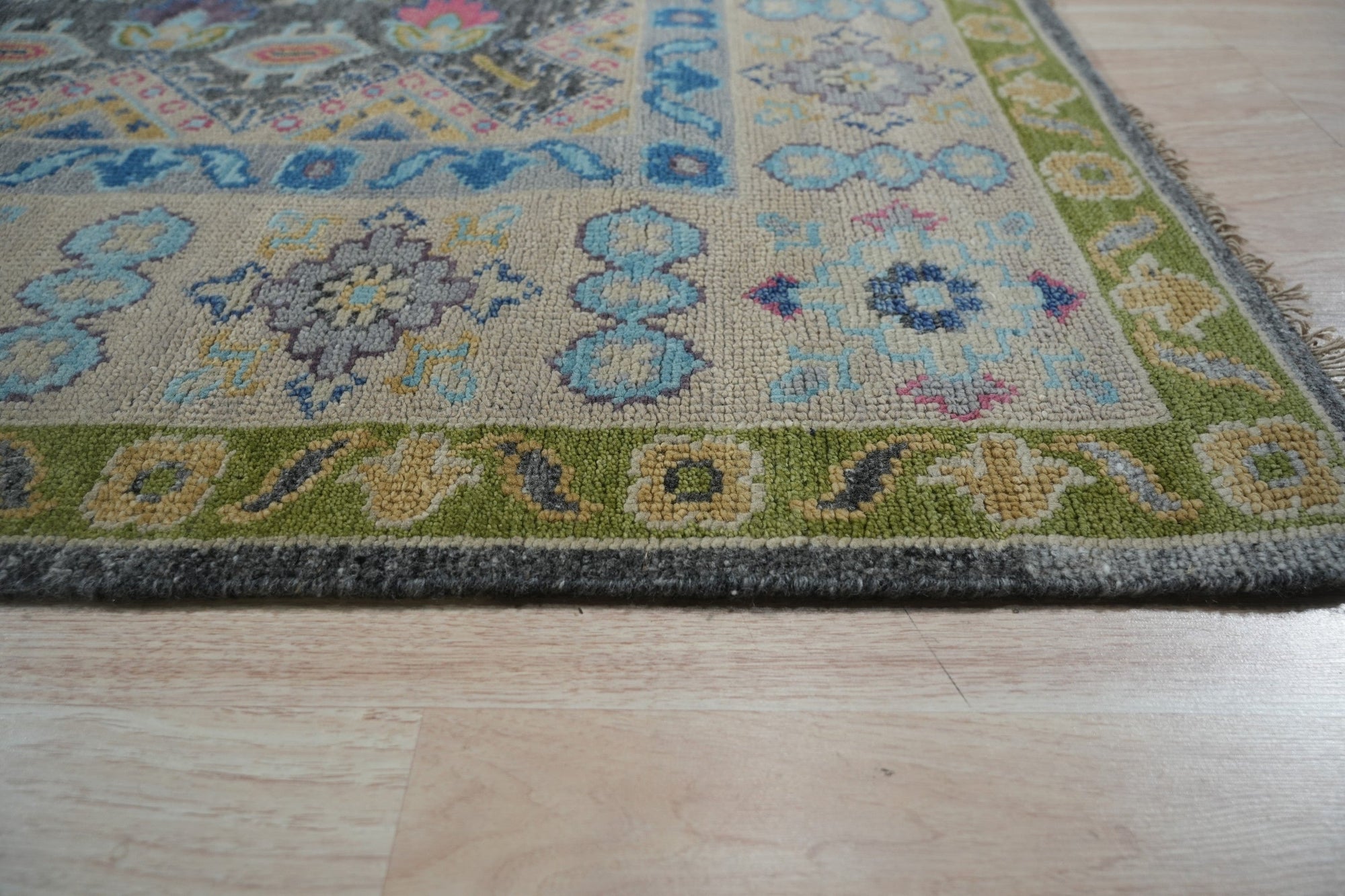 Maya Kazak Charcoal Hand Knotted Wool Rug, its intricate geometric pattern rendered in shades of charcoal wool, lies flat revealing depth and texture in its hand-knotted construction.