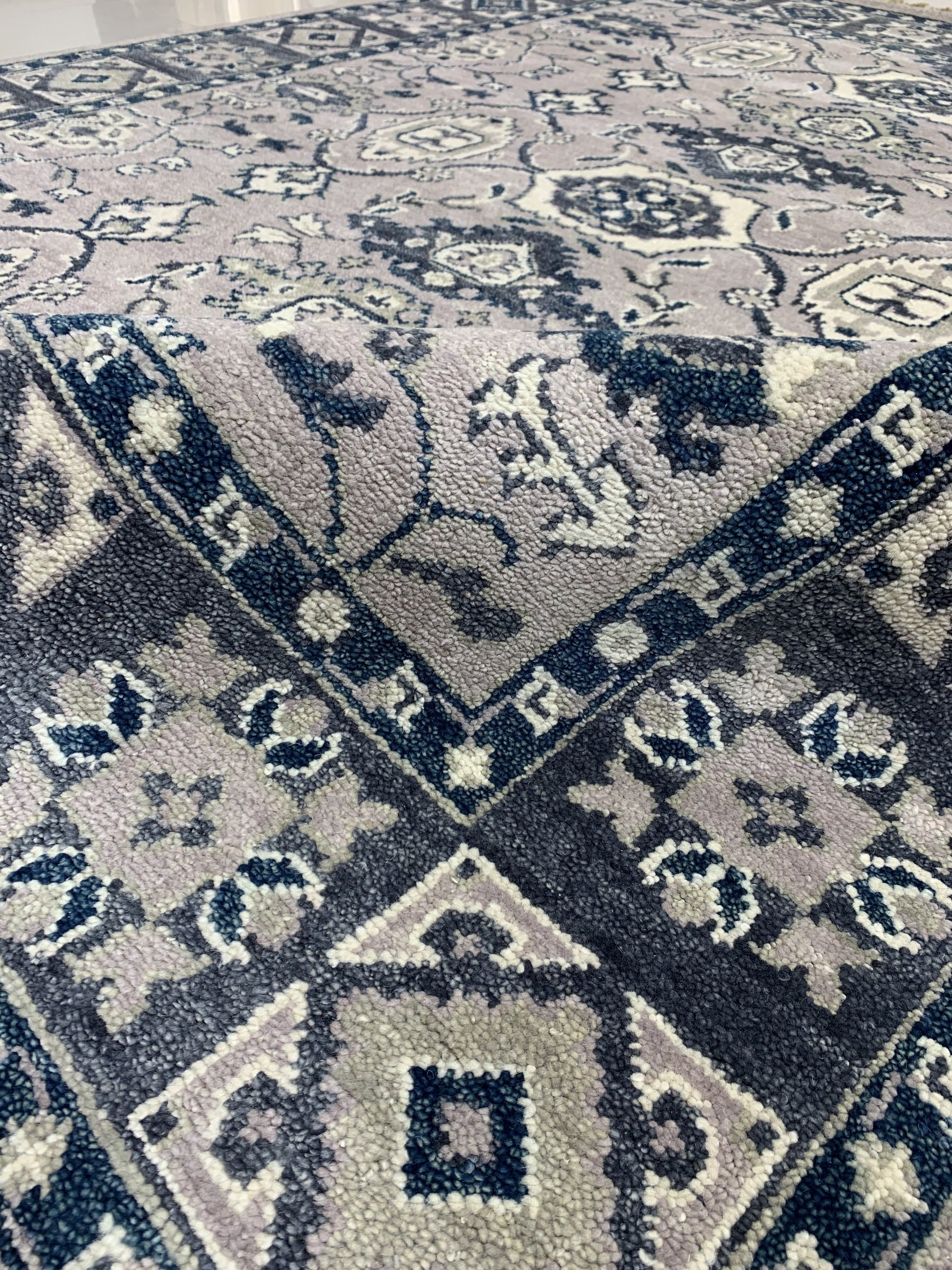 Captivating Jasmine Gray Hand Knotted Wool Rug displayed on a light wooden floor, its intricate hand-knotted construction visible in the soft grey wool pile.