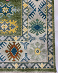 Inviting Kazak Light Green Hand Knotted Wool Rug, a light green wool rug hand-knotted with geometric designs, displayed in a room setting with neutral walls and furniture.