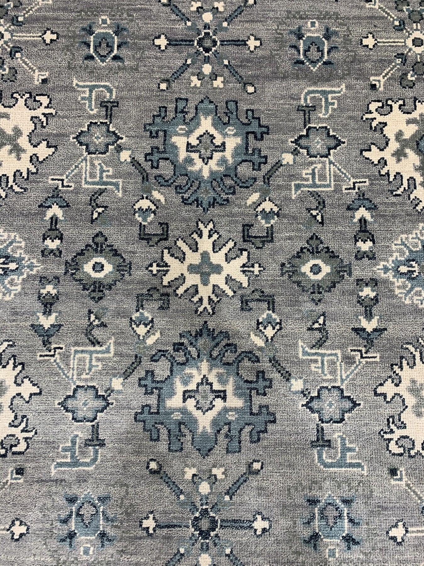 Maya Oushak Silver Hand Knotted Wool Rug, displaying its intricate, traditional Oushak design in muted silver and ivory tones, laying elegantly on a hardwood floor.