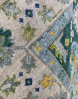 Isla Kazak Green Hand Knotted Wool Rug, its intricate geometric patterns and vibrant green hues enriching a living room setting with hardwood floors and neutral furniture.