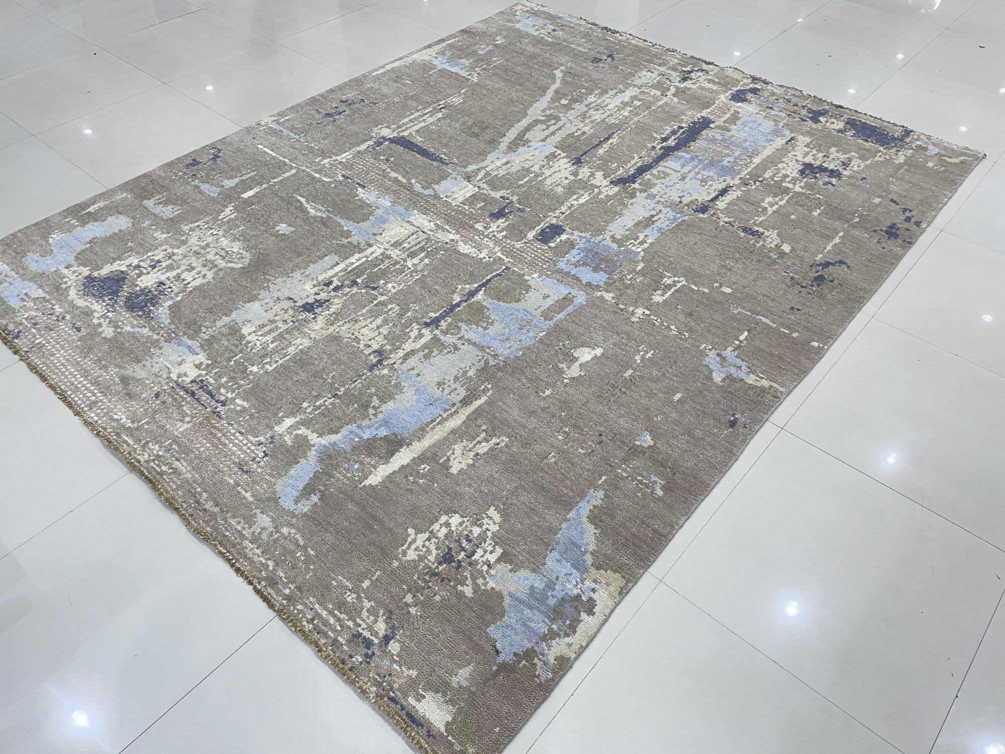 Clara Stylish Gray Hand Knotted Wool Rug, showcasing a subtle textured weave in varying shades of gray, lies flat on a light hardwood floor with a modern, minimalist aesthetic.
