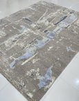 Clara Stylish Gray Hand Knotted Wool Rug, showcasing a subtle textured weave in varying shades of gray, lies flat on a light hardwood floor with a modern, minimalist aesthetic.