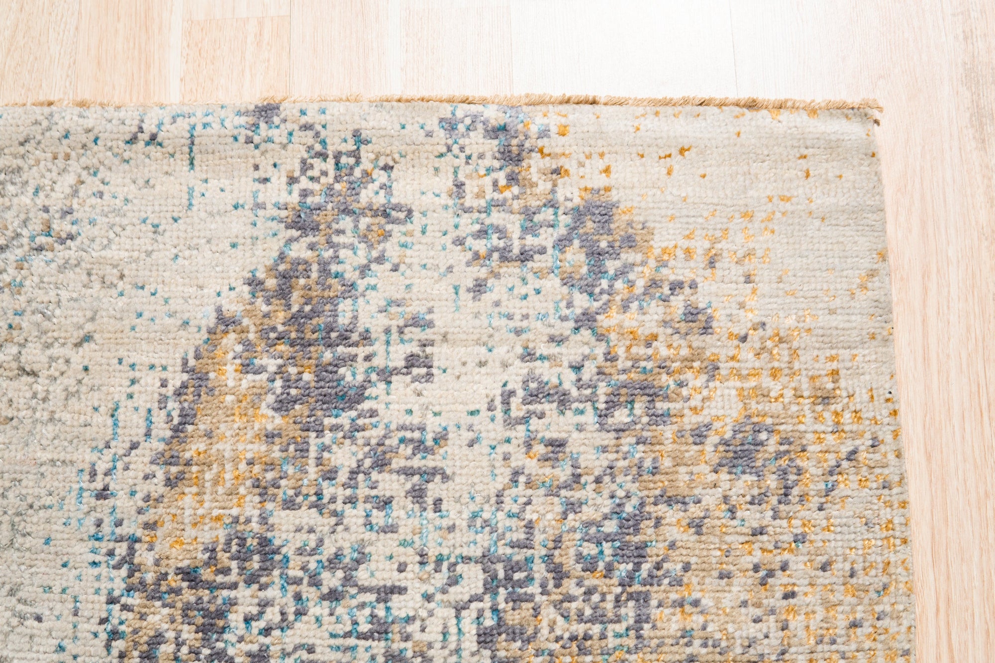 Lydia Cassandra Gray Hand Knotted Wool Rug, displaying intricate geometric patterns in shades of gray and cream, rests on a light wood floor, adding warmth and texture to a neutral space.