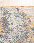 Lydia Cassandra Gray Hand Knotted Wool Rug, displaying intricate geometric patterns in shades of gray and cream, rests on a light wood floor, adding warmth and texture to a neutral space.