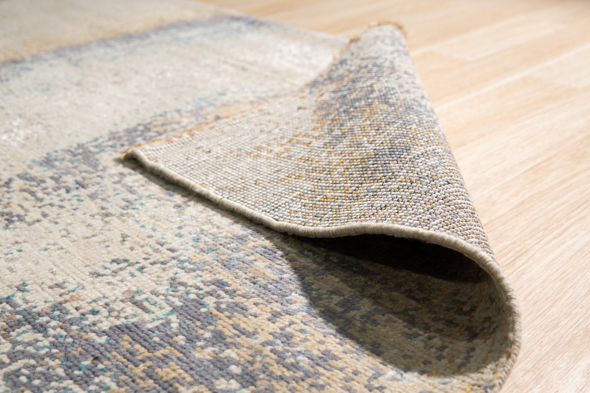 Lydia Cassandra Gray Hand Knotted Wool Rug, its intricate design partially visible, showcasing a blend of neutral grays in a hand-knotted wool construction, lending warmth and texture to the modern space.