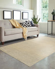 Celia Lila Ivory Hand Knotted Wool Rug, softly patterned in ivory and muted lilac tones, sits on a light hardwood floor, enhancing a bright, airy living space.