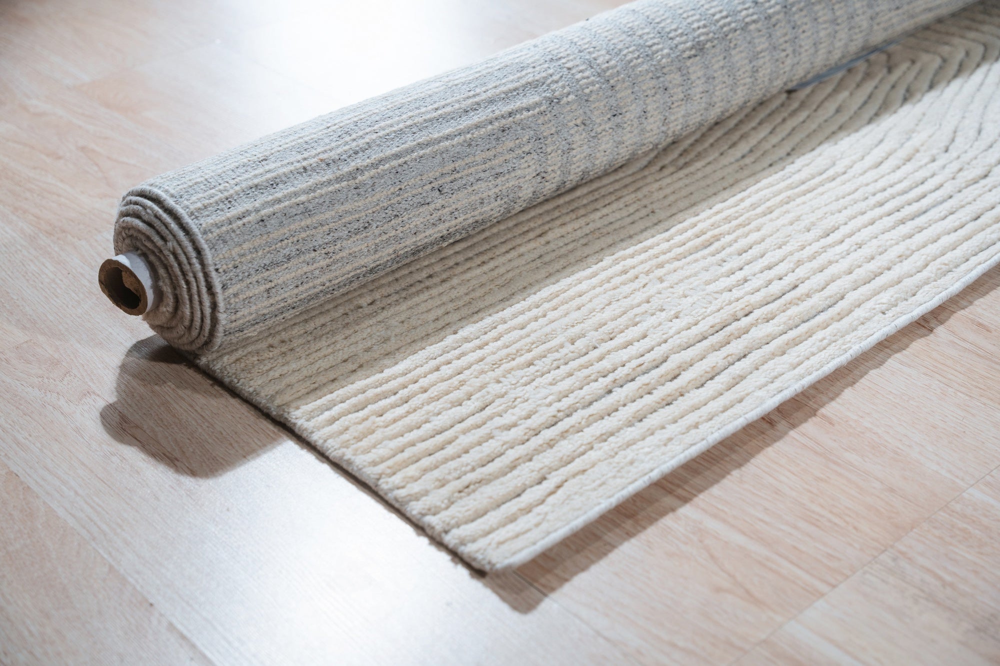 Celia Lila Ivory Hand Knotted Wool Rug, a blend of soft lilac and ivory, rests on a light hardwood floor, its hand-knotted wool pile offering subtle texture and warmth to the room.