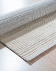 Celia Lila Ivory Hand Knotted Wool Rug, a blend of soft lilac and ivory, rests on a light hardwood floor, its hand-knotted wool pile offering subtle texture and warmth to the room.