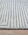 Celia Lila Ivory Hand Knotted Wool Rug, a soft ivory rug with subtle lilac accents, displayed in a brightly lit interior space. Fine wool construction and hand-knotted details are visible.