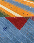 Timeless Gabbeh Blue Handmade Wool Rug, displaying vibrant blues and earthy neutrals in a geometric, hand-knotted design.