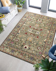 Ophelia Oriental Green Hand Knotted Wool Rug, showcasing intricate floral patterns in varying shades of green, cream, and muted reds, displayed in a bright living room setting with contemporary furniture.