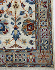 Iris Oushak Beige Hand Knotted Wool Rug, showcasing intricate floral and geometric patterns in soft beige tones, lies elegantly on a wooden floor, suggesting a warm and inviting interior space.