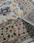 Iris Oushak Beige Hand Knotted Wool Rug, seen in a room setting, highlights the rug's intricate Oushak pattern in soft beige tones, showcasing its handcrafted wool construction.