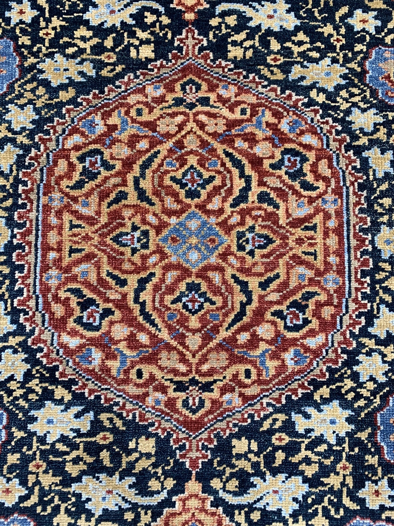 Bianca Traditional Navy Hand Knotted Wool Rug, showcases its intricate traditional pattern in deep navy blue and ivory tones, hand-knotted construction visible, softening a warmly lit space.