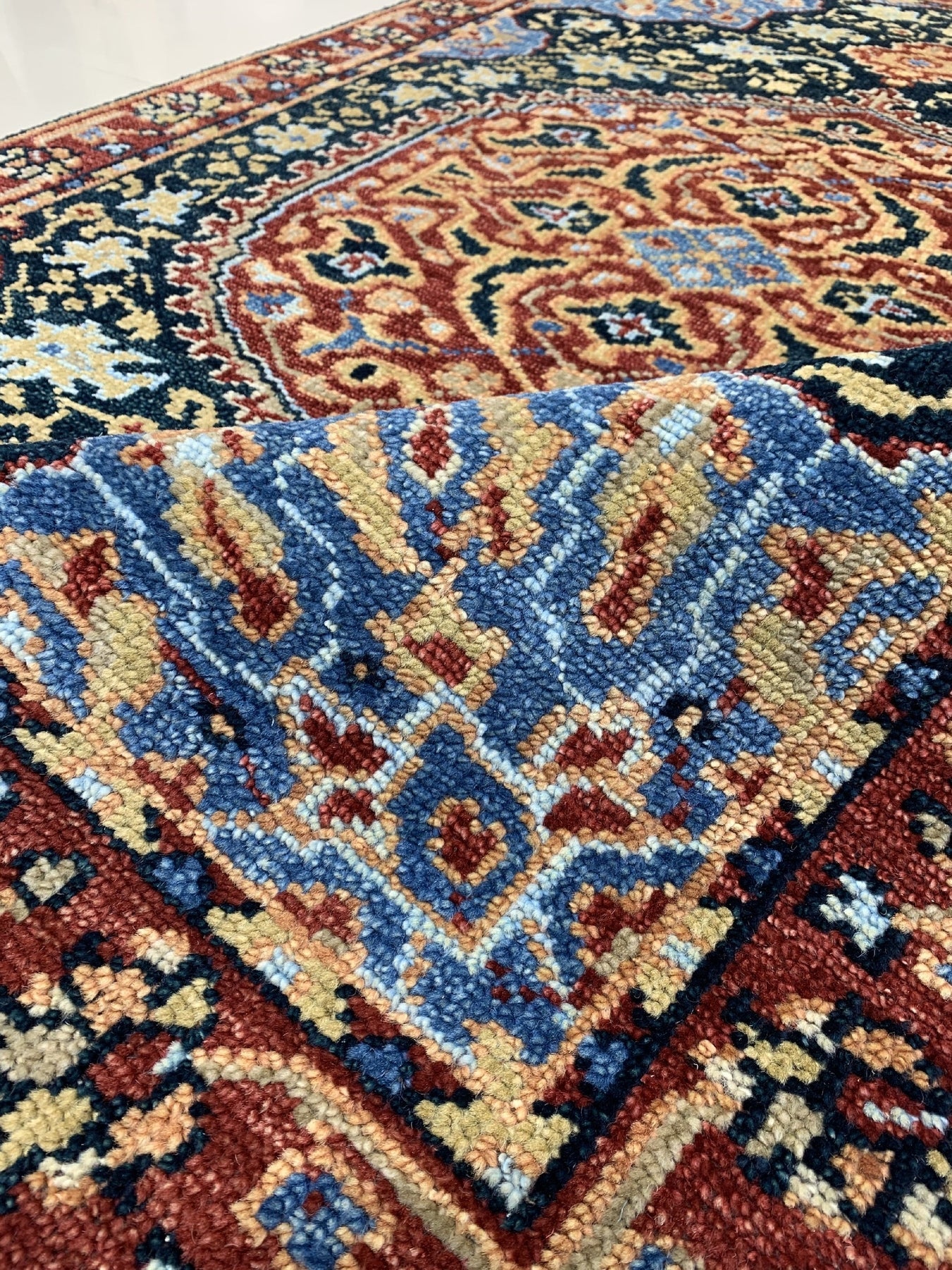 Bianca Traditional Navy Hand Knotted Wool Rug, displaying intricate patterns in deep navy and lighter blues, softening the well-lit living space with classic elegance.