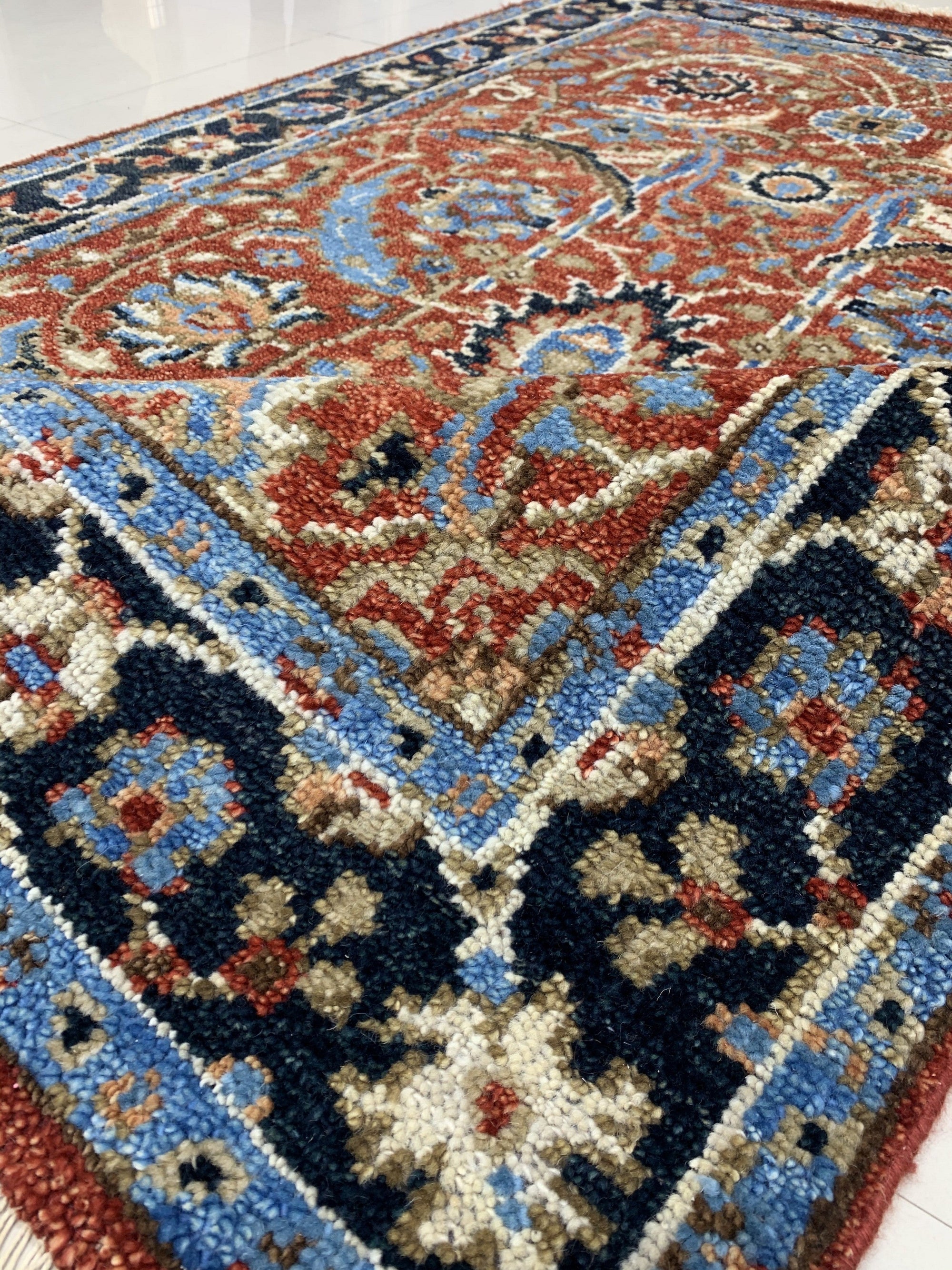 Rustic Oriental Red Hand Knotted Wool Rug, vibrant reds and earthy tones blend in a traditional Oriental pattern. Hand-knotted wool creates depth and texture under soft, diffused lighting. Rich colors evoke warmth and comfort.