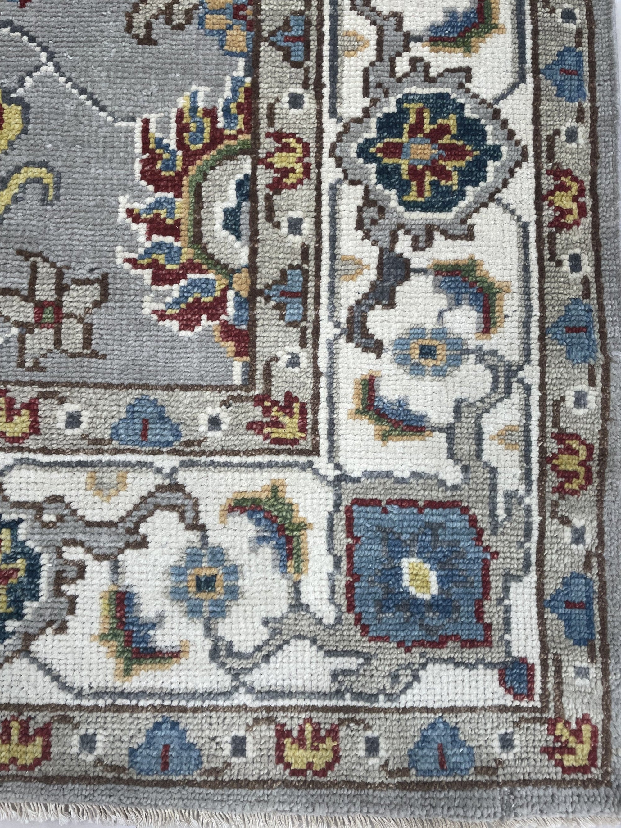Enchanting Oriental Gray Hand Knotted Wool Rug, featuring intricate floral and geometric patterns in shades of gray and ivory, lies flat on a light-colored floor, its hand-knotted wool construction creating a soft and inviting texture.