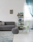 Trara Nadia Blue Hand Tufted Wool Rug, presenting intricate geometric patterns in shades of blue, cream, and beige, laid on a light hardwood floor enhancing its textured wool construction.