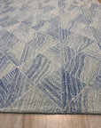 Trara Nadia Blue Hand Tufted Wool Rug, a captivating blend of cool blues and subtle creams, offers a luxurious underfoot experience with its hand-tufted wool construction, presented in a room setting that highlights its calming presence.