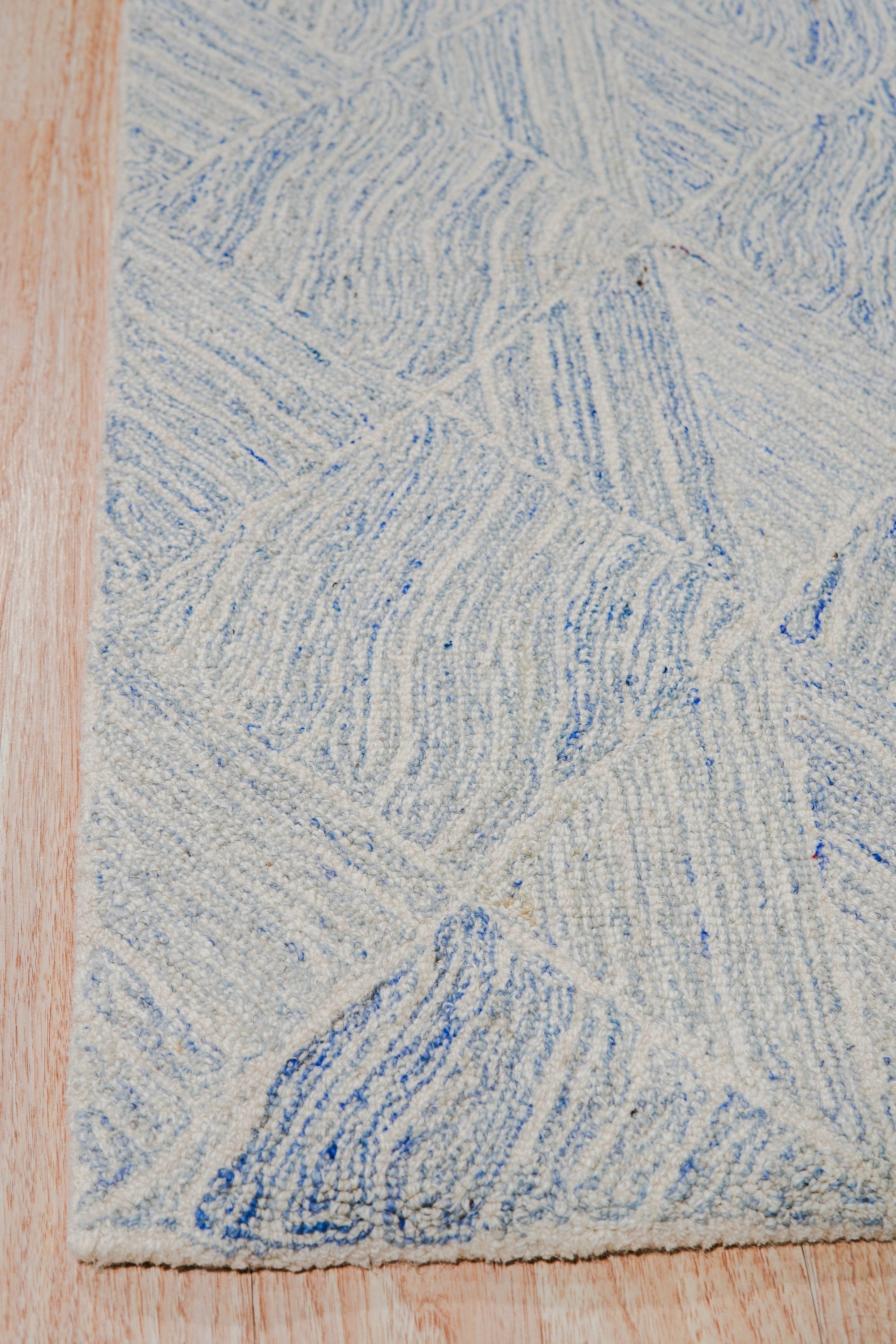 Trara Nadia Blue Hand Tufted Wool Rug, vibrant blue and cream wool rug with a geometric, almost Moroccan-inspired pattern, seen in a brightly lit, neutral-toned living space, lending warmth and visual interest.