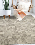Nina Rustic Gray Hand Tufted Wool Rug, its subtle gray tones and hand-tufted texture adding warmth to a bright living space with modern furniture and a cozy fireplace.