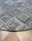 Nina Rustic Gray Hand Tufted Wool Rug, blending soft gray tones and rustic textures, graces a warmly lit living space. Hand-tufted wool construction promises comfort and durability.