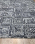 Nina Rustic Gray Hand Tufted Wool Rug, showcasing its muted gray tones and textured, rustic design in a styled interior setting. Hand tufted wool creates a warm, inviting feel.