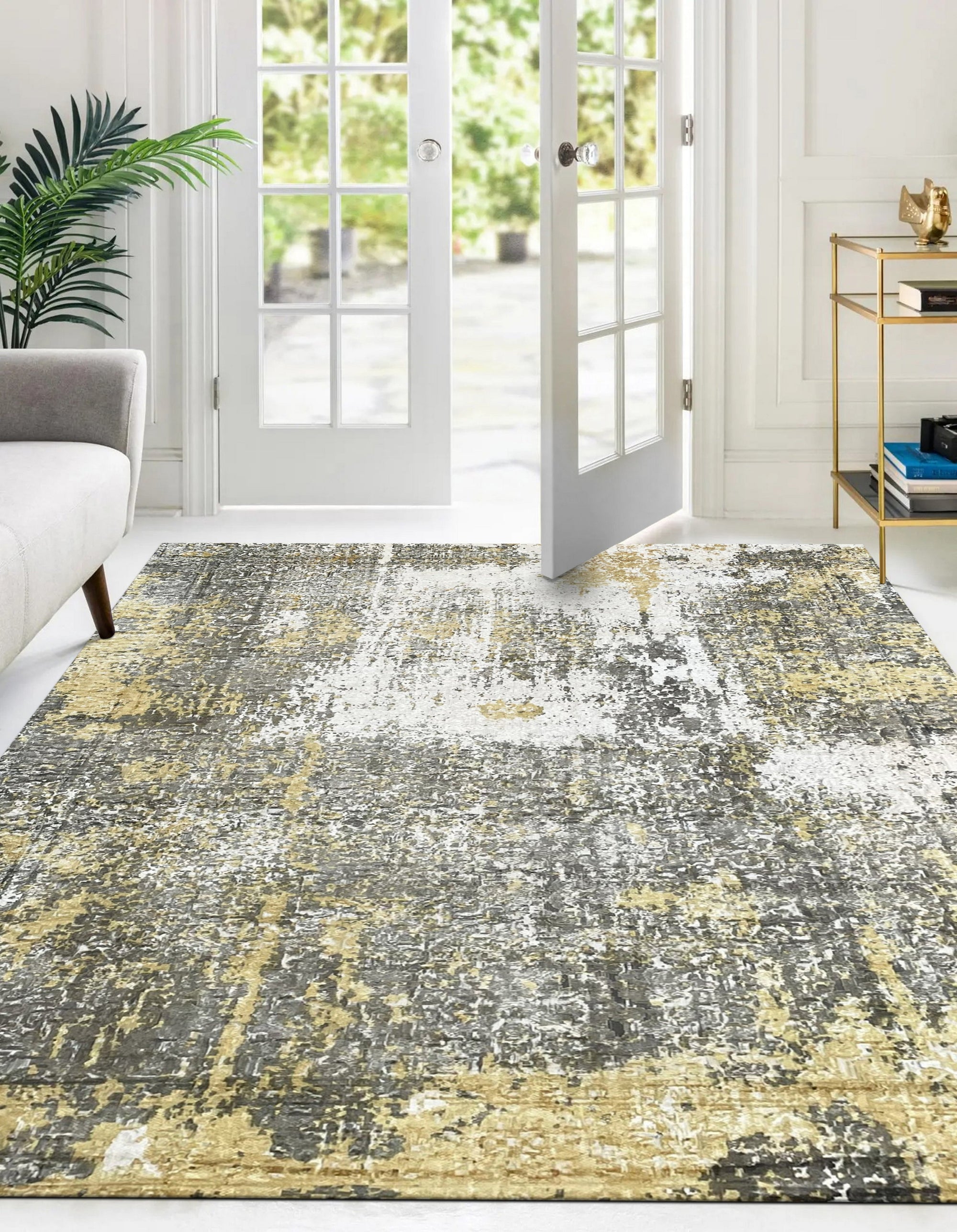 Chic Iris Gold Hand Knotted Wool Rug, its swirling gold and cream patterns catching the light, sits elegantly on a dark hardwood floor. The hand-knotted construction is evident in the subtle texture, creating a warm and inviting focal point in the room.