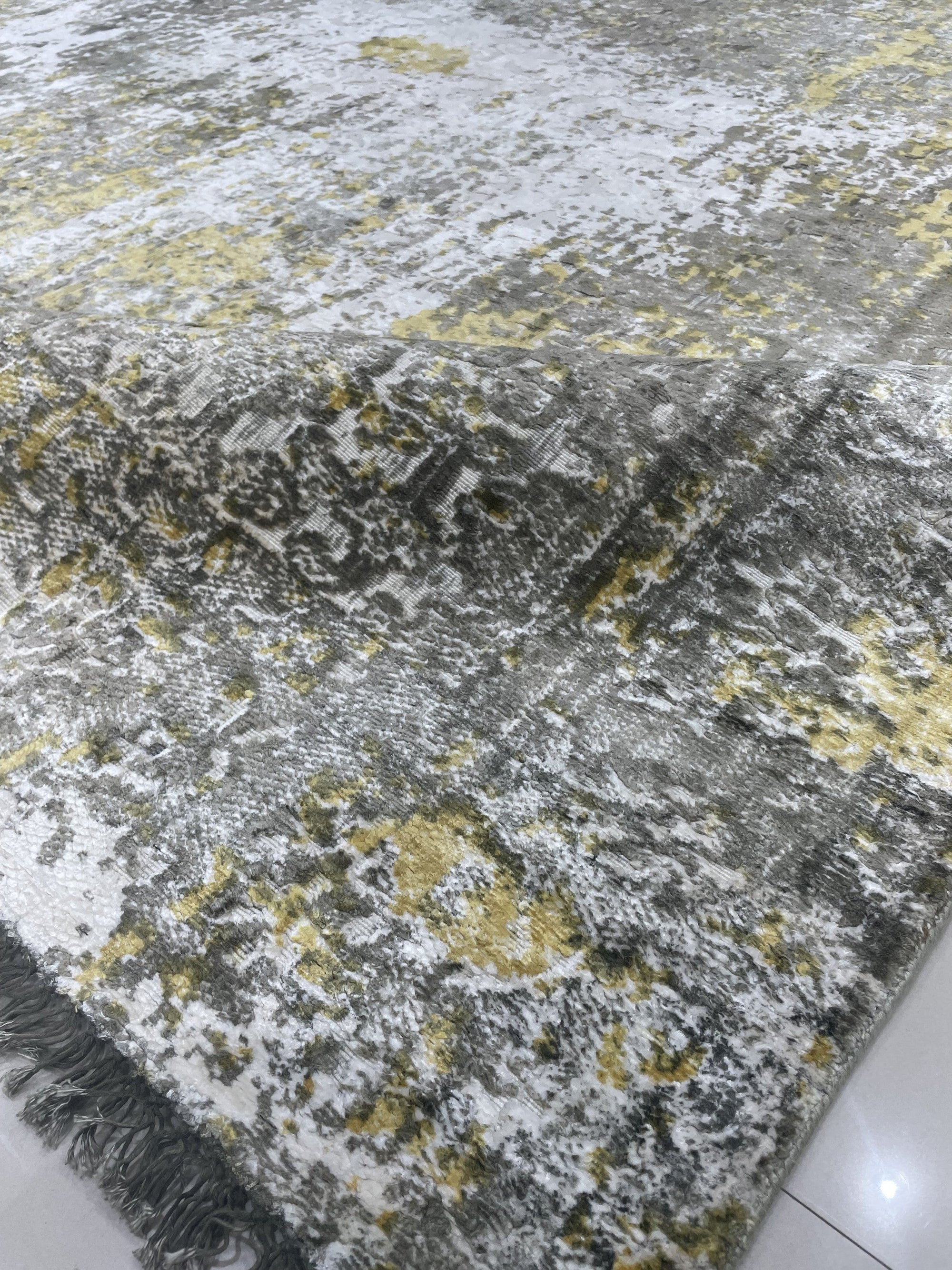 Chic Iris Gold Hand Knotted Wool Rug, showcasing shimmering gold hues and an intricate iris-inspired design in a lifestyle setting. Hand-knotted wool construction adds texture and luxury to the room.